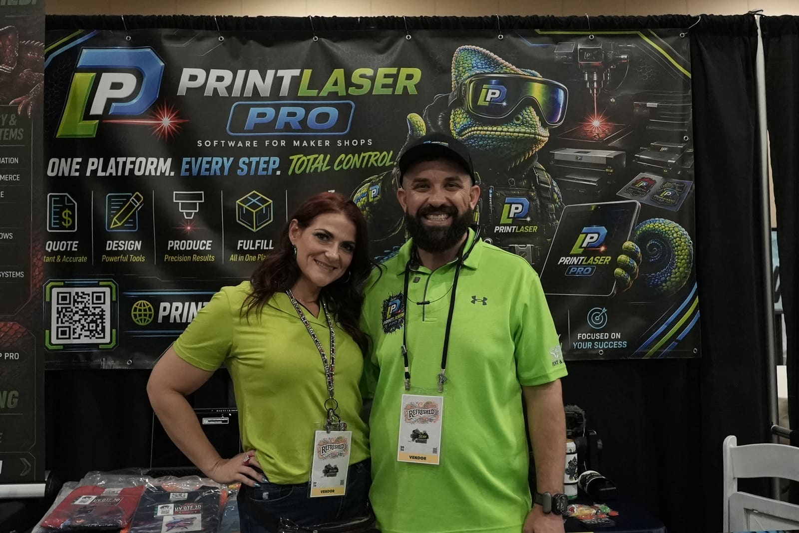 Sean Gilliland and Brittany, cofounder and partner, in lime Print Laser Pro polos at the official Prizmo booth wall during Next Level Maker 2026.